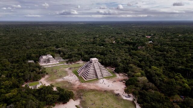Wide orbit shot of the Temple of Kukulcan at Chichen Itza in Yucatan, Mexico, revealing its ancient architecture and jungle surroundings