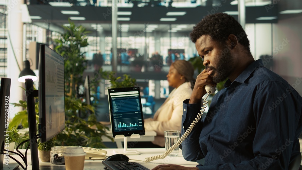 Poster close up of worker in office using landline phone to talk with customer. african american employee a