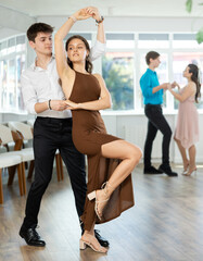 Fototapeta premium Couple in festive clothes learn to dance latin american dance bachata in studio
