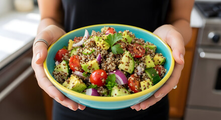 Woman holding a bowl of quinoa salad with avocado tomatoes and red onion