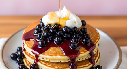 Delicious pancakes topped with blueberries whipped cream and maple syrup
