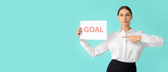 Young businesswoman holding paper with word GOAL on color background