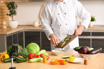 Male chef with fresh vegetables recording cooking video in kitchen