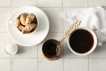 Sugar in bowl, cezve and cup of coffee on light background