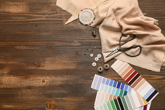 Composition with color samples and sewing accessories on wooden brown background. Top view