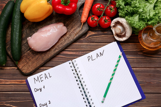 Healthy products and weekly meal plan on wooden background. Diet concept