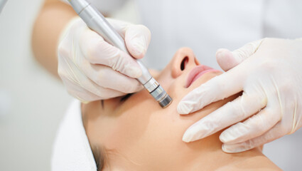 Professional beautician performing a microdermabrasion treatment on woman's face at beauty clinic, providing skincare, cleansing, and rejuvenation procedures for healthy skin