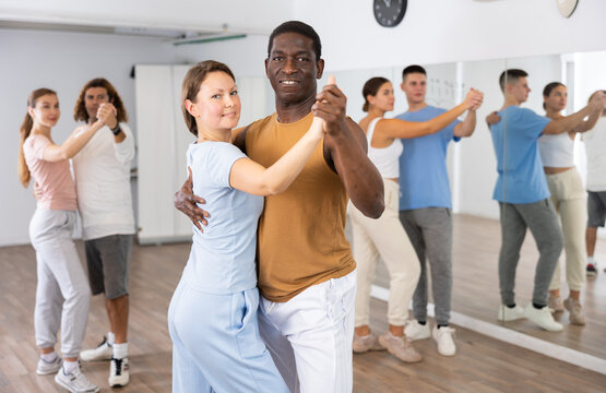Group of diverse happy adult people dancing modern social dances in pairs at fitness studio - Powered by Adobe