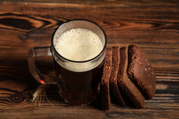 Mug of fresh kvass and slices of bread on wooden background