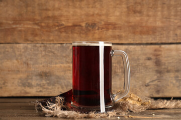 Mug of fresh kvass and wheat on wooden background
