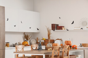 Interior of light kitchen decorated for Halloween with counters, table and pumpkins