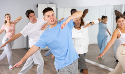 Group of positive dancers repeat dance in dance hall