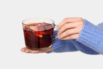Young woman holding glass cup of hot mulled wine on white background, closeup