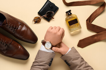 Male hands with stylish accessories and leather shoes on beige background