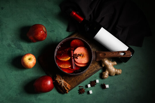 Saucepan of hot mulled wine and ingredients on green background - Powered by Adobe