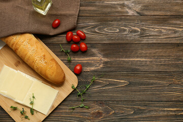 Board with slices of delicious processed cheese, fresh tomatoes and bread on wooden table