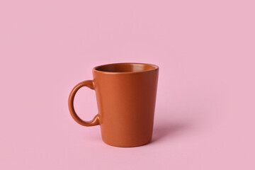 Brown ceramic empty mug on pink background