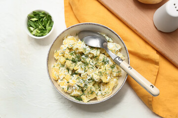 Bowl of tasty potato salad with dill and green onion on white background