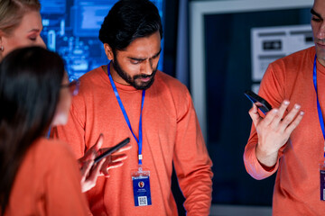 A data analytics team in a command center cross references information from a mobile device with a...