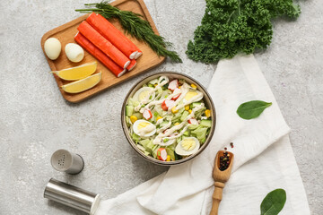Bowl of salad with crab sticks, iceberg leaves, corn, quail eggs and cucumber on grey grunge background © Pixel-Shot