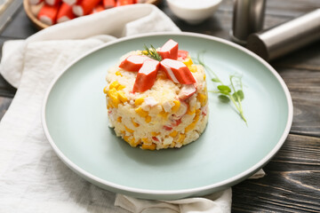 Plate of salad with crab sticks and corn on wooden background