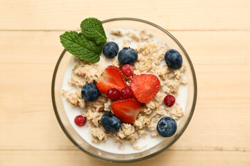 Bowl with tasty oatmeal and berries on wooden background