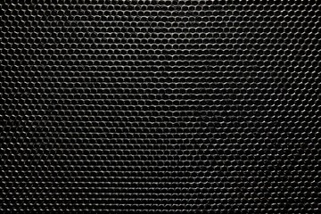 Close-up view of a dark, textured, grid-like surface.  Small, round, embossed dots form a repeating pattern.  Slight variations in light create subtle highlights and shadows