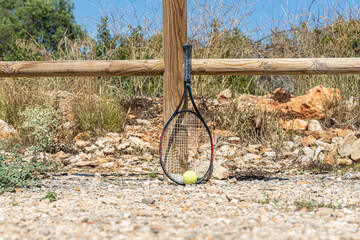 Tennis racket and ball by wooden fence
