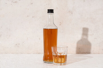 Bottle and glass of rum with ice cubes on white background