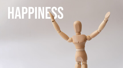 Concept of happiness. A wooden mannequin with its arms raised and the word happiness.