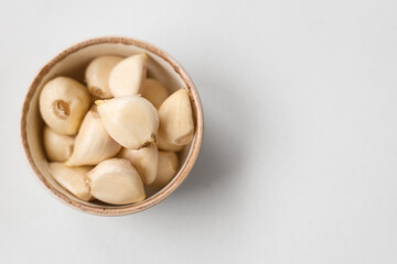 Bowl with fresh garlic cloves on white background