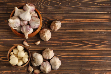 Bowls with fresh garlic and cloves on wooden background