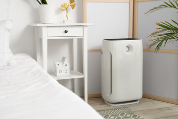Air purifier near folding screen in light bedroom