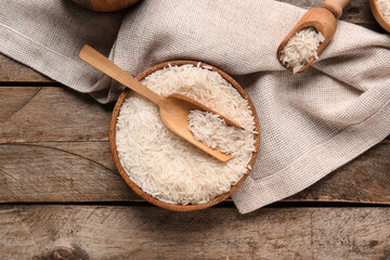 Bowl and scoops with raw rice on wooden background