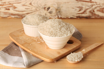 Bowels and spoon of rice on table against white wooden background. Closeup
