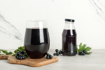 Glass and bottle of fresh black currant juice on white background