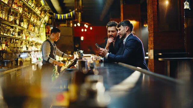 Pub visitors using smartphone discussing social media content in restaurant
