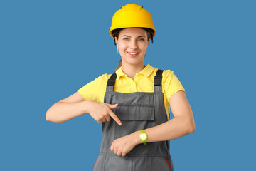 Female worker pointing at wristwatch on blue background. Time management concept