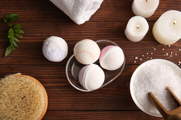 Composition with tray, bath bombs and burning candles on brown wooden background