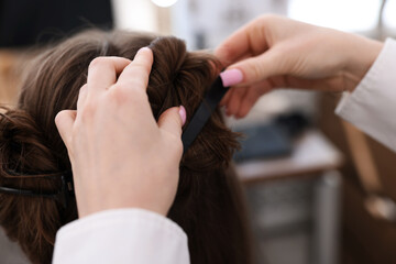 Fototapeta premium Professional hairstylist working with client in salon, closeup