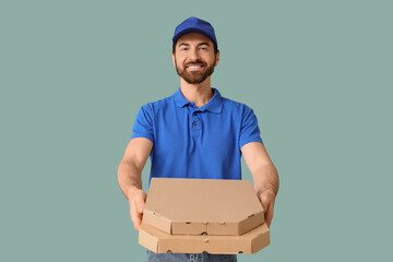 Male courier with pizza boxes on green background
