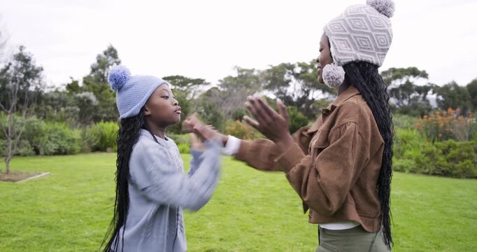 African American sisters in knit hats raising hands starting clapping game in yard and hugging