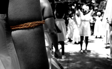 Black and white photograph focused on an arm, with blurred people in the background during a Candombl&eacute; ritual.