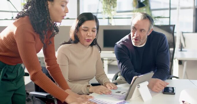 Prompted by charts Diverse colleagues at workspace pointing and tapping tablet to reach consensus