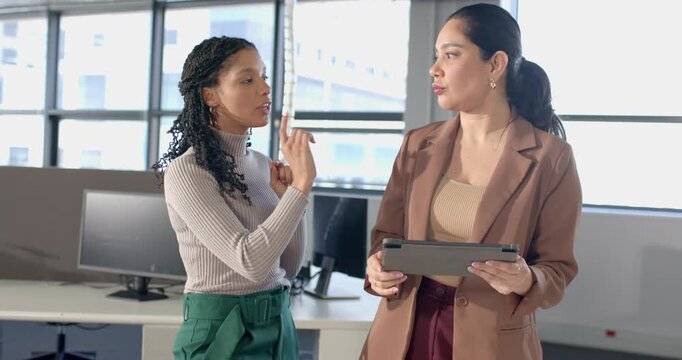 Diverse female colleagues using tablet and gesturing plan, smiling and high-fiving in office