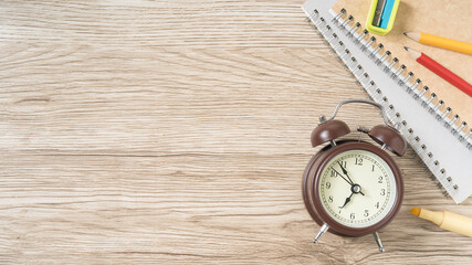 Time to get creative with school supplies and an old-fashioned alarm clock on a warm wooden desk, perfect for back-to-school ads and social media