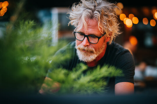 Thoughtful senior man with glasses white beard sitting outdoors looking down - Powered by Adobe