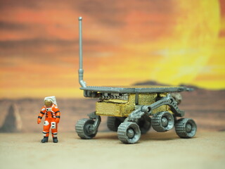 Mini toy of action figure at table with blurred background. Toy photography concept design. Astronaut landing at new planet conceptual. Exploring space with mars rover.