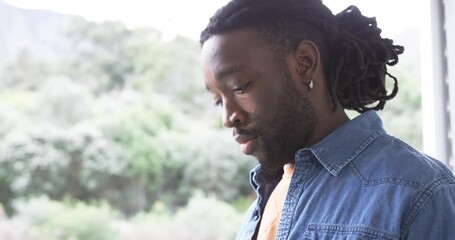 Scrolling feed, African American man lifting rose-case phone to ear calling on balcony, copy space - Powered by Adobe
