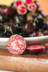 Fresh Wild Red Ginseng Fruit from Yunnan China Sliced Open Showing Pink Interior and Seeds on Wooden Board